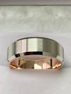 a wedding band with two tone gold inlays on the inside of it, sitting on top of a white cloth