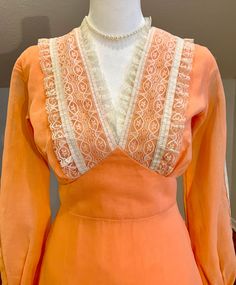 "Lovely apricot/peach color prairie dress with cream color lace trim. This 70's dress is in amazing vintage condition! There is a small amount of fraying on the side where the tie sash meets the waistband. It isn't really noticeable but please see the last photo for details. There is no maker's tag but there is a dry clean only tag stitched into the back lower lining of the dress. This dress looks handmade otherwise.  Zips up the back and ties with sash. Hook and eyes. Snaps at the wrist.  Measurements taken flat and are approximate. Please measure carefully as I don't take refunds but feel free to message me with any questions. Waist: 13\" (x2) Bust: 17\" (x2) blousy top Hips: 18\" (x2) Length: 54\" Sleeve length: 22\" Would best fit a size Small"