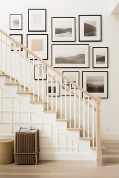 a staircase with pictures on the wall and a basket under it in front of some stairs