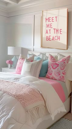 a white bed with pink and blue pillows