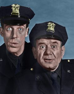 two men dressed in uniforms are posing for a black and white photo, one is surprised