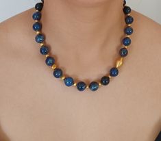 Sophisticated handcrafted beaded necklace features a single strand of natural Lapis Lazuli gemstone beads.  This unique necklace is beautifully embellished with small 22K Gold wax filled  beads and accented with one larger bead in the front. Secures with a 14K Gold lobster clasp. Length 47 cm (18.5 inches) Lapis Lazuli beads 12.5 mm Small gold beads range in size 3 mm to 7 mm Large gold bead 10 mm x 20 mm; thickness 11.5 mm 14K gold clasp 15 mm x 5 mm One of a kind.  Made in Greece. All items ar Luxury Lapis Lazuli 8mm Bead Jewelry, Luxury Lapis Lazuli Beaded Necklace With Natural Stones, Luxury Single Strand Lapis Lazuli Necklace, Luxury Gold Lapis Lazuli Beaded Necklace, Luxury Gold Beaded Lapis Lazuli Necklace, Luxury Lapis Lazuli Beaded Necklaces With Round Beads, Luxury Lapis Lazuli Gemstone Beads Jewelry, Luxury Elegant Lapis Lazuli Beaded Necklaces, Luxury Lapis Lazuli Round Bead Necklaces