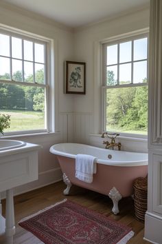 an old fashioned bathtub in the corner of a bathroom with two windows and a rug on the floor