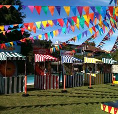 many colorful flags are hanging from the sky above an amusement park ride and swimming pool