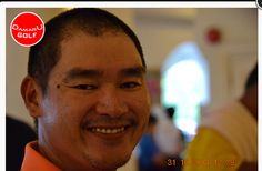 a man smiling for the camera with an orange shirt on and red tie around his neck