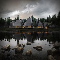 a group of buildings sitting on top of a lake next to rocks and trees in the background