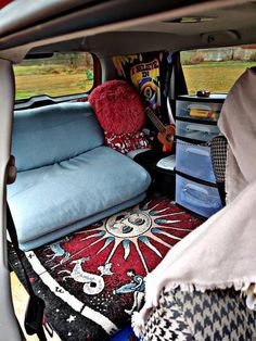 the back seat of a van is filled with furniture and blankets, including a guitar