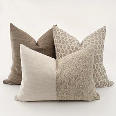 four pillows are stacked on top of each other in different colors and sizes, one is brown