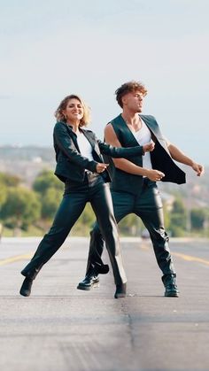 two people dressed in black and white are walking down the street with their arms around each other