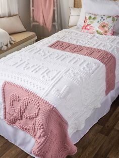 a pink and white crocheted bedspread on a bed in a bedroom