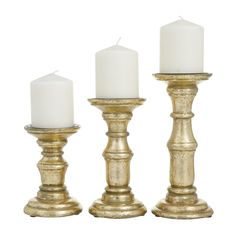 three gold candlesticks with white candles in them