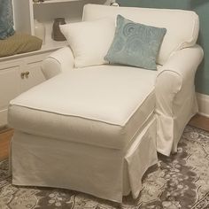 a white chair with a blue pillow on top of it in front of a mirror