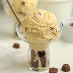 two scoops of ice cream in a glass bowl with chocolate chips on the side