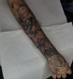 a person's arm with a flower and butterfly tattoo on the left side of their arm