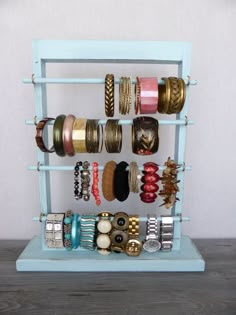 a blue shelf with bracelets and rings on it's sides, in front of a white wall