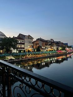 a view of the water and buildings at dusk from a balcony in front of a restaurant