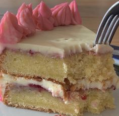 a piece of cake with white frosting and raspberries on top is being held by a fork