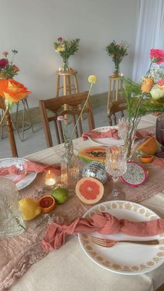 the table is set with plates and flowers in vases, candles, and napkins