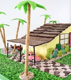 a cake that is shaped to look like a house with cars and palm trees on it