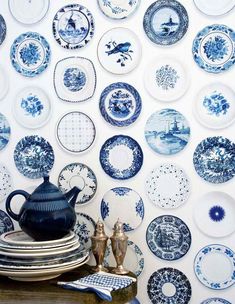 blue and white plates are arranged on the wall behind a table with a teapot