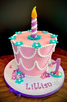 a pink birthday cake with a candle on top