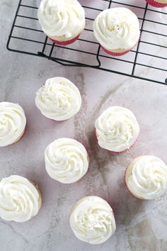 cupcakes with white frosting sitting on a cooling rack