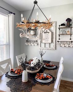 a dining room table decorated for halloween with candles, plates and napkins on it