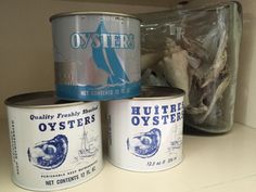 three cans of oysters sitting on top of a counter next to a bag of crackers