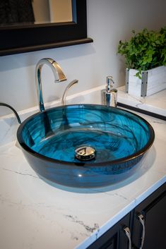 a blue glass bowl sink sitting on top of a white counter next to a mirror