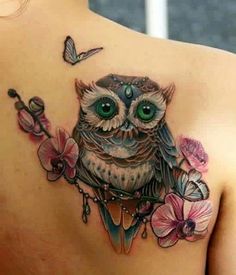 an owl with green eyes is on the back of a woman's shoulder and has pink flowers around it