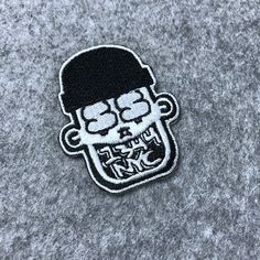 a black and white embroidered patch with a skull wearing a hat on it's head