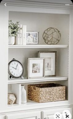 a white book shelf filled with pictures and other items next to a clock on top of a dresser