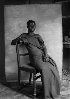 an old black and white photo of a woman sitting in a chair