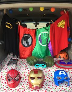 the back of a car filled with superhero masks and t - shirts hanging from hooks