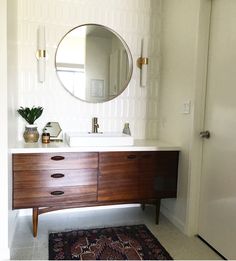 a bathroom with a sink, mirror and rug