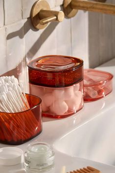 toothbrushes and soaps are sitting on the edge of a bathtub next to a sink