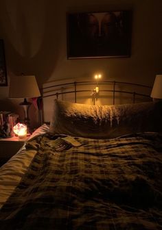 a bed with a plaid comforter and two candles on the headboard in front of it