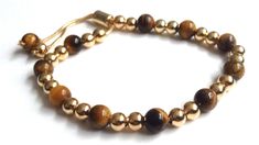 "Tigers Eye Bracelet This modern and stunning Shamballa bracelet is made with an adjustable chain brass 18k gold plated and beaded with an 8mm genuine tiger eye beads, and gold-filled balls. It is a nice piece for everyday use and combines with any casual outfit. This is a perfect Birthday, graduation, Christmas or Mothers day gift. The bracelet is adjustable to any wrist size with a comfortable sliding clasp closure. It can be adjusted from 6\" to 9\" inches approximately. Each item is carefull Gold Adjustable Bracelet With Sliding Knot, Adjustable Gold Bracelet With Sliding Knot, Gold Adjustable Resizable Bracelet, Adjustable Gold Rosary Bracelet, Gold Bracelets With Adjustable Round Beads, Gold Bracelets With Adjustable Length And Round Beads, Resizable Gold Beaded Bangle Bracelets, Adjustable Gold Plated Beaded Bracelets With Round Beads, Adjustable Gold Crystal Bracelet With Round Beads