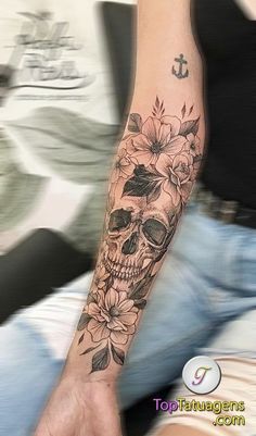 a person with a skull and flowers tattoo on their arm