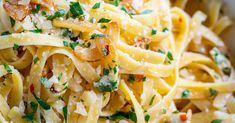 a bowl filled with pasta covered in parmesan cheese and garnished with herbs