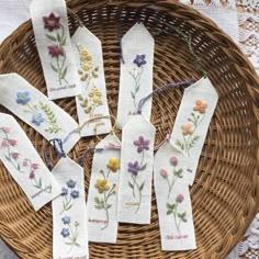 four embroidered bookmarks with flowers on them in a wicker basket