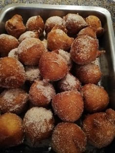 a metal pan filled with sugar covered donuts