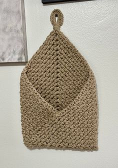 a crocheted bag hanging on the wall next to a framed photograph with a hook