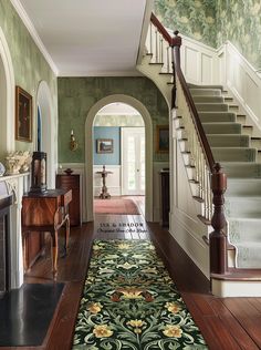 the hallway is decorated in green and white with floral rugs on the hardwood floor