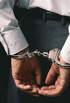 a man in white shirt and black pants holding his hands together with handcuffs on their wrists