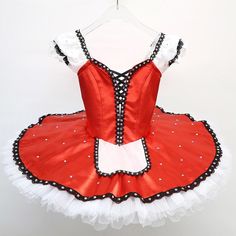 a red and white tutu with polka dots on the bottom is hanging from a hanger