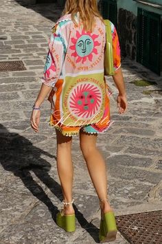 a woman is walking down the street in her colorful dress and green shoes with an open toed sandal