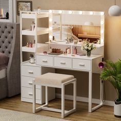 a white vanity with lights on it in a room next to a chair and potted plant