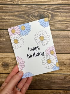 someone holding up a birthday card with daisies on it