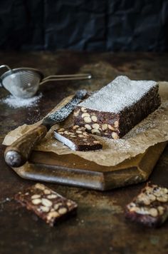 some brownies are sitting on a cutting board with powdered sugar and a spatula